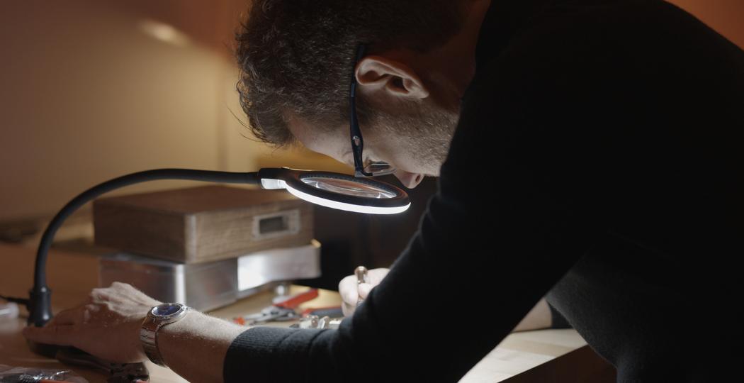 Geoff Evans refining a Memories Lockbox at his workbench under a magnifier lamp